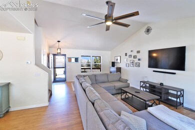 Living room featuring vaulted ceiling, ceiling fan