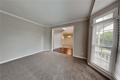 Spare room featuring dark carpet, baseboards, orna
