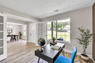 Office area featuring light wood finished floors, a chandelier, and a textured ceiling