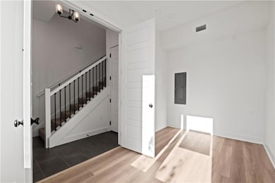 Staircase with a notable chandelier, hardwood / wood-style flooring, and electric panel