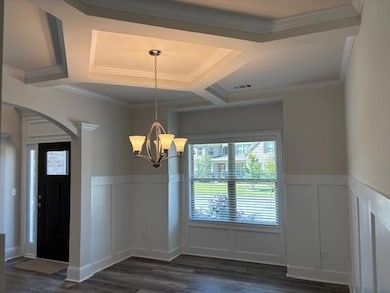 Unfurnished dining area featuring arched walkways, a decorative wall, dark wood-style flooring, a chandelier, and coffered ceiling