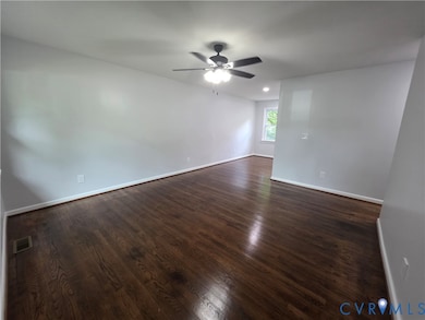 Spare room with dark wood-type flooring and a ceiling fan