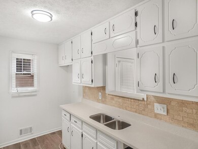 Kitchen with white cabinetry, a sink, backsplash, 