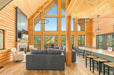 Living area with log walls, high vaulted ceiling, a chandelier, light wood-style floors, and wood ceiling