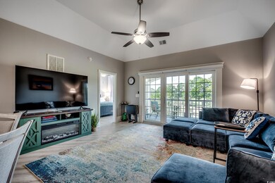 Living room featuring light wood-style flooring, ceiling fan, and vaulted ceiling