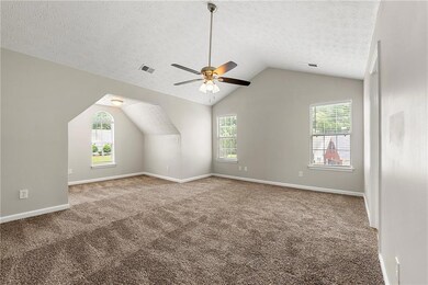 Bonus room with lofted ceiling, a ceiling fan, carpet, and a textured ceiling