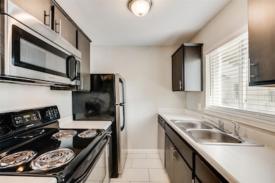 Kitchen with baseboards, a sink, appliances with s