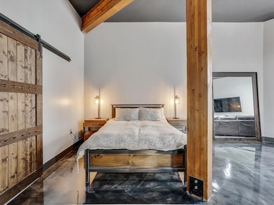 Bedroom with a barn door, concrete flooring, and b