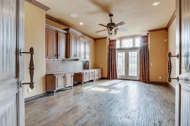 Unfurnished office with crown molding, built in study area, light wood-style flooring, french doors, and ceiling fan