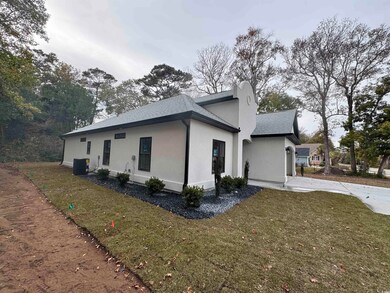 View of side of home with a shingled roof, stucco siding, and a lawn