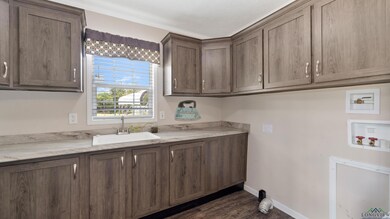 Laundry room with hookup for a washing machine, cabinet space, dark wood finished floors, and crown molding