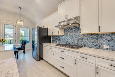 Kitchen featuring under cabinet range hood, appli