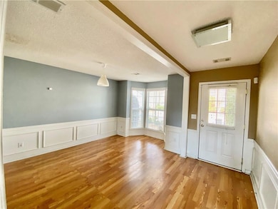Entryway featuring wainscoting, a textured ceiling, a decorative wall, and wood finished floors