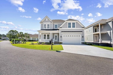 View of front facade with covered porch, driveway, an attached garage, a front lawn, and a standing seam roof