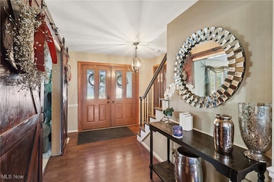 Foyer entrance with a barn door, wood finished floors, and a chandelier