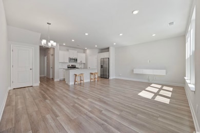 Unfurnished living room with a chandelier, recessed lighting, and light wood-style flooring