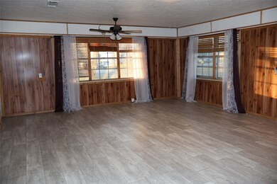 Unfurnished room with a textured ceiling, a ceiling fan, wood finished floors, and wooden walls