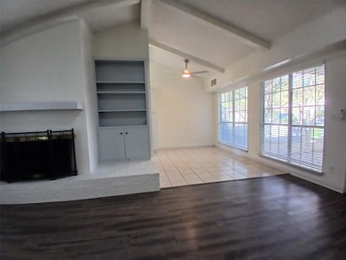 Unfurnished living room featuring light wood finished floors, built in shelves, ceiling fan, and a fireplace
