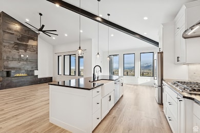Kitchen with white cabinets, hanging light fixtures, backsplash, a large fireplace, and a spacious island