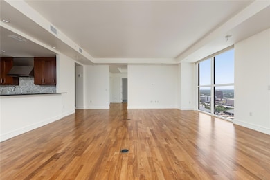 Unfurnished living room featuring light wood-style floors, expansive windows, a view of city, and a tray ceiling