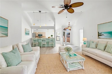 Living room featuring high vaulted ceiling, ceiling fan, and light wood finished floors