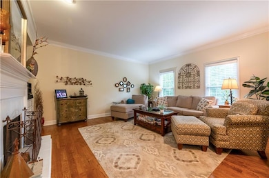 Living room featuring crown molding, wood finished floors, and a tiled fireplace