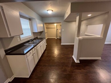 Kitchen featuring a sink, white cabinetry, baseboa
