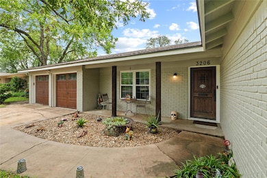 Property entrance with a garage, brick siding, driveway, and a porch