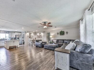 Living room featuring a textured ceiling, dark wood-type flooring, ceiling fan, recessed lighting, and crown molding