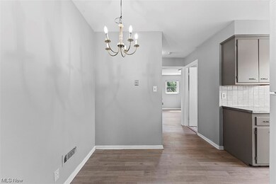 Kitchen featuring a notable chandelier, gray cabinetry, decorative light fixtures, backsplash, and light wood-type flooring