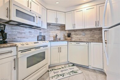Kitchen with white appliances, white cabinetry, an