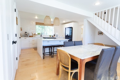 Dining area featuring light wood-type flooring, recessed lighting, and stairs