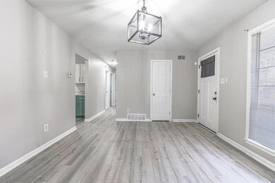 Unfurnished living room with light wood-style floors, a textured ceiling, and a chandelier