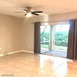 Tiled spare room featuring a ceiling fan and baseb