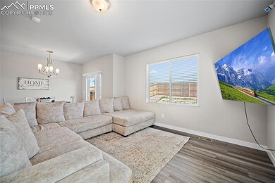 Living area with a chandelier, wood finished floors, and baseboards