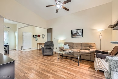 Living room featuring a ceiling fan, light wood fi