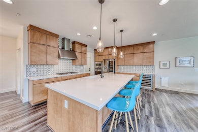 Kitchen with a sink, wall chimney range hood, ligh