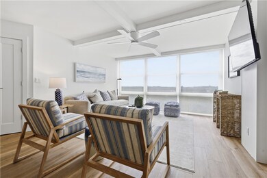 Living room with beamed ceiling, light wood-type flooring, floor to ceiling windows, and ceiling fan