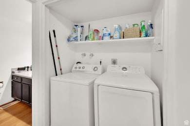 Washroom with independent washer and dryer and light wood finished floors