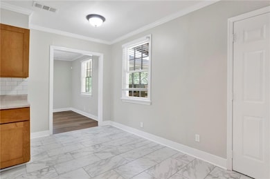 Unfurnished dining area featuring ornamental molding and light marble finish floors