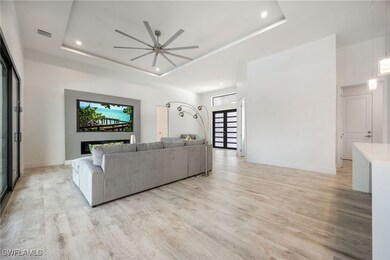 Living area featuring a tray ceiling, a ceiling fa