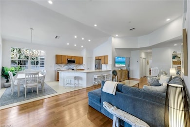 Living room featuring recessed lighting, light wood-style floors, a chandelier, and high vaulted ceiling