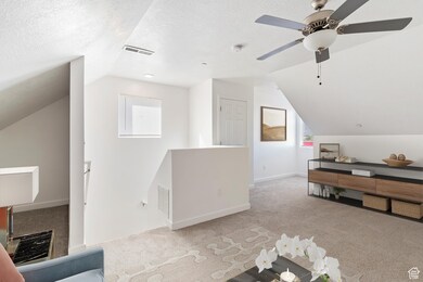Additional living space featuring vaulted ceiling, carpet floors, a textured ceiling, and ceiling fan. Staged