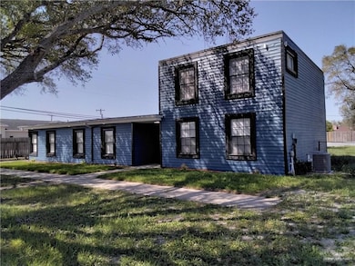 View of front of house featuring central air condition unit, fence, and a front lawn