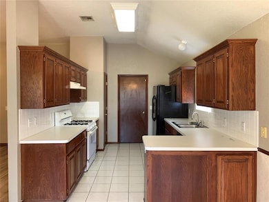 Kitchen featuring white gas range, a sink, light countertops, vaulted ceiling, and decorative backsplash