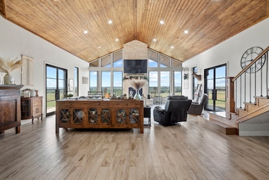 Living room with high vaulted ceiling, light wood-type flooring, and wooden ceiling