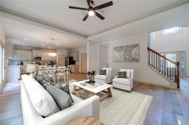 Living room with light wood finished floors, stairs, and ceiling fan