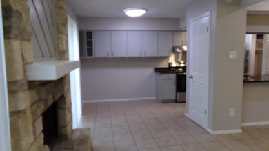 Kitchen featuring white cabinets, light tile patterned floors, electric range, a stone fireplace, and extractor fan