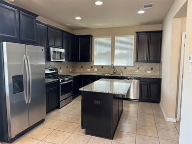 Kitchen with appliances with stainless steel finishes, backsplash, light stone counters, light tile patterned floors, and recessed lighting