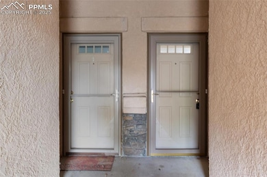 Property entrance featuring stucco siding and stone siding